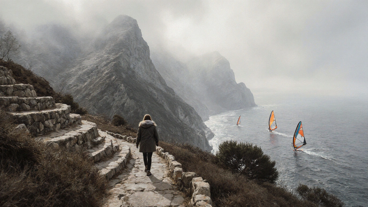 Sendero de la Serra de Tramuntana en invierno con un excursionista y windsurfistas al fondo.